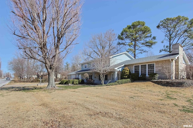 view of front facade with stone siding, a chimney, and a front yard