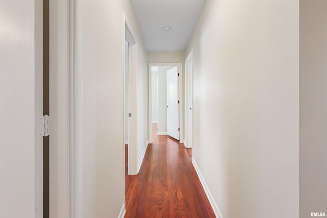 hallway with dark wood-style flooring and baseboards