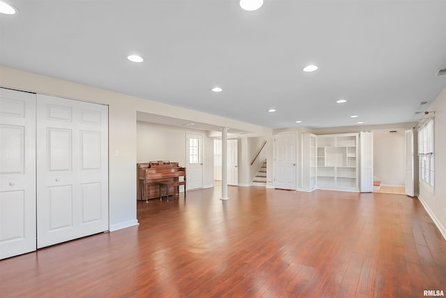 basement featuring recessed lighting, wood-type flooring, stairway, and baseboards