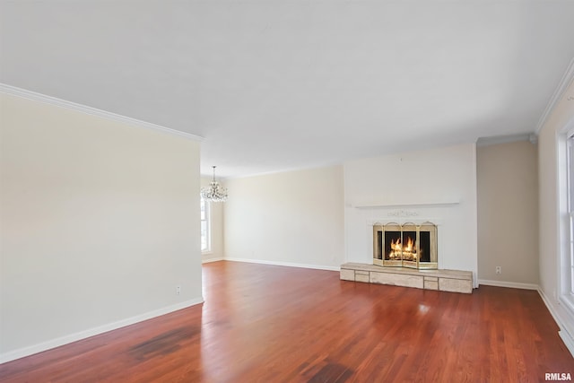 unfurnished living room with a warm lit fireplace, ornamental molding, wood finished floors, and baseboards