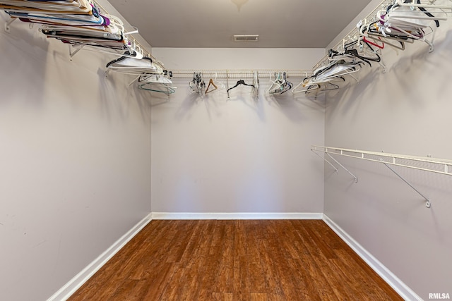 walk in closet with visible vents and dark wood finished floors