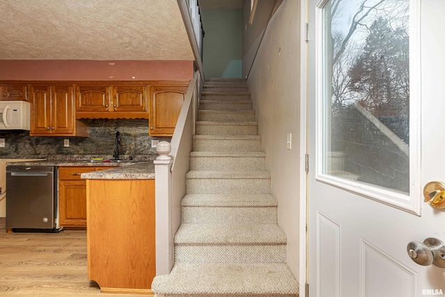 stairway with a textured ceiling and wood finished floors