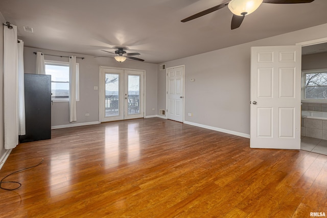 unfurnished living room featuring french doors, wood finished floors, and baseboards