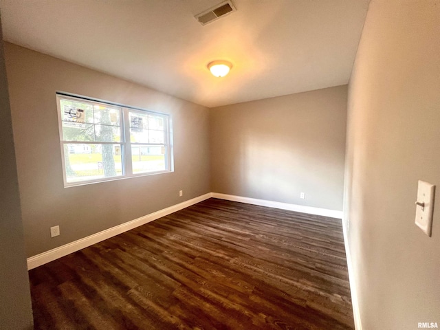 spare room featuring dark wood-type flooring, baseboards, and visible vents