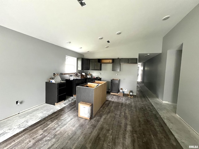 kitchen with dark wood finished floors, a center island, and vaulted ceiling