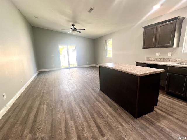 kitchen with visible vents, a kitchen island, light countertops, vaulted ceiling, and dark wood-style flooring