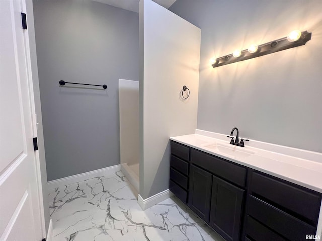 full bathroom featuring walk in shower, baseboards, marble finish floor, and vanity