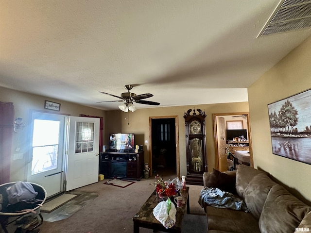 living room featuring visible vents, ceiling fan, a textured ceiling, and carpet