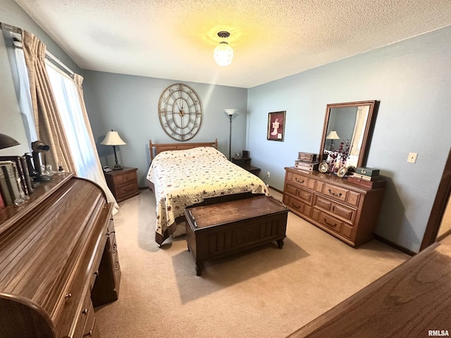 bedroom featuring baseboards, light carpet, and a textured ceiling