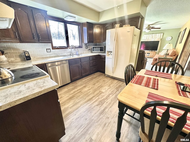 kitchen with tasteful backsplash, dark brown cabinets, light wood-style flooring, stainless steel appliances, and a sink