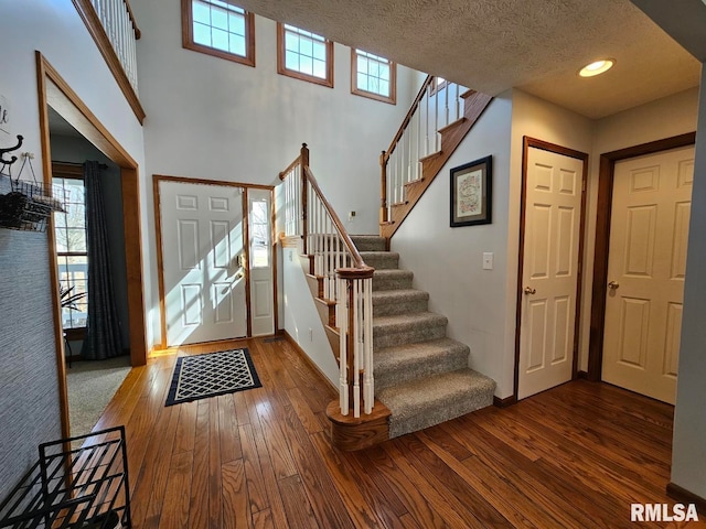 entryway with a textured ceiling, stairs, baseboards, and wood-type flooring