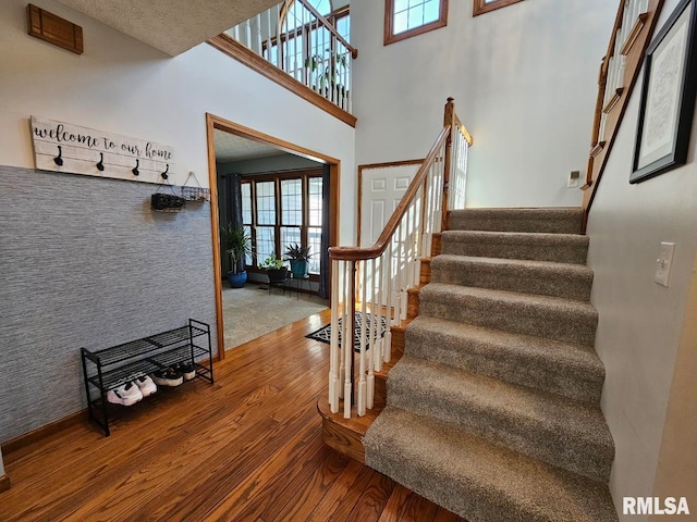 stairs with a high ceiling and wood finished floors