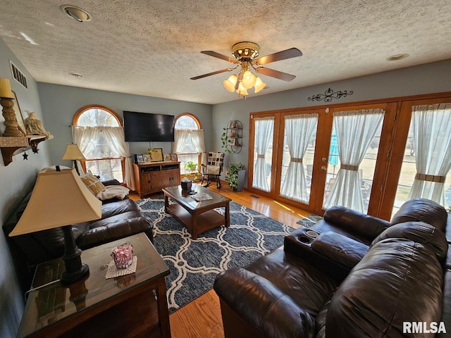 living area with visible vents, a textured ceiling, and wood finished floors