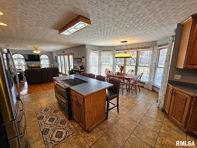 kitchen with dark countertops, a center island, stainless steel appliances, and a wealth of natural light