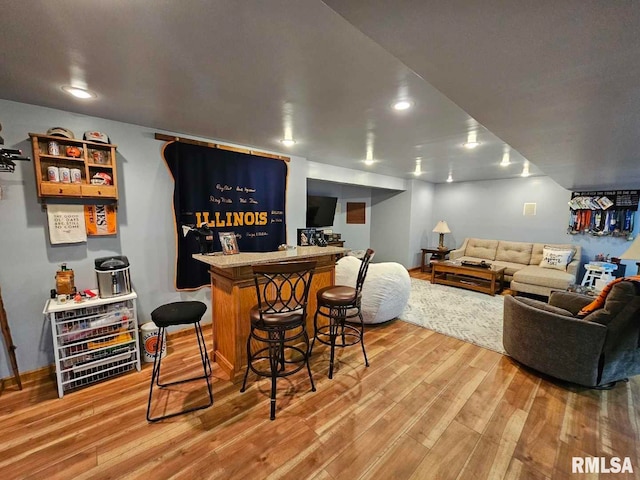 bar featuring light wood-type flooring, baseboards, and a bar