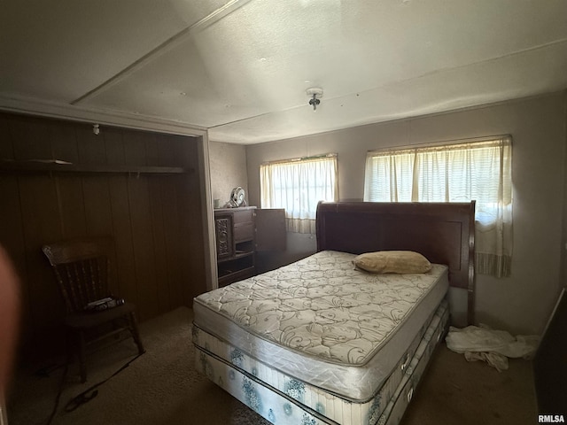 carpeted bedroom featuring wooden walls