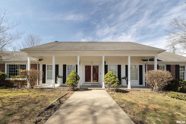 view of front of property with brick siding, a porch, and roof with shingles