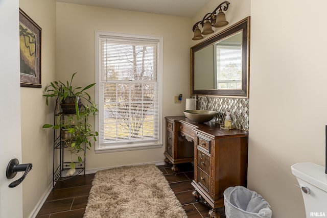 bathroom featuring a wealth of natural light, baseboards, toilet, and vanity