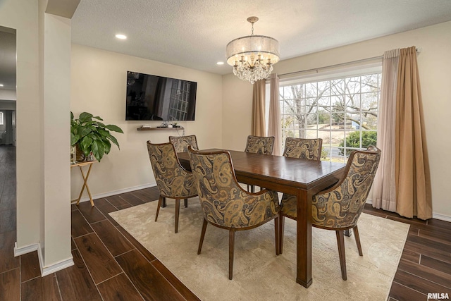 dining space with a textured ceiling, baseboards, and wood finish floors