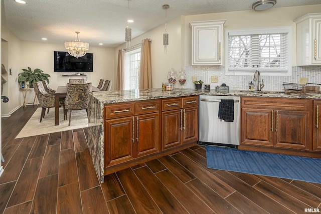 kitchen with wood finish floors, stone countertops, a sink, stainless steel dishwasher, and backsplash