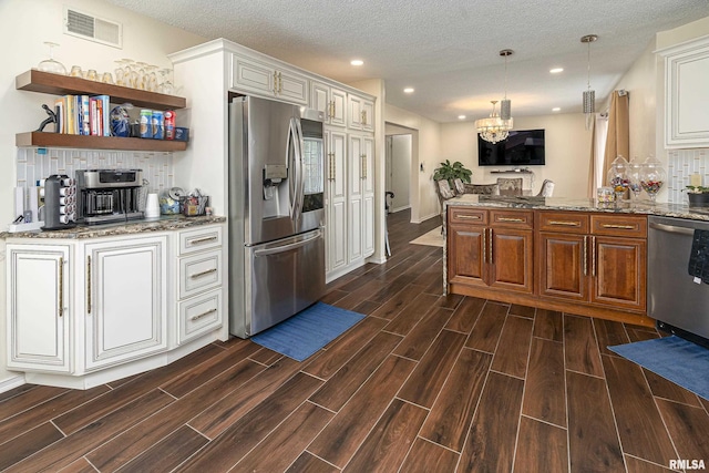 kitchen with wood finish floors, visible vents, stone countertops, decorative light fixtures, and appliances with stainless steel finishes