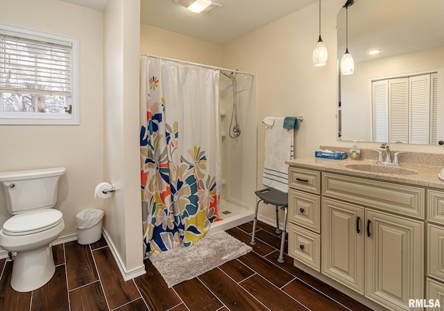 full bath with wood finish floors, toilet, a stall shower, baseboards, and vanity