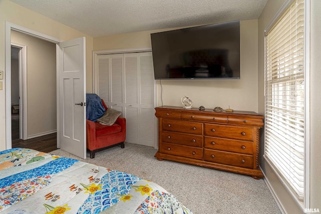 carpeted bedroom with a closet, a textured ceiling, and baseboards