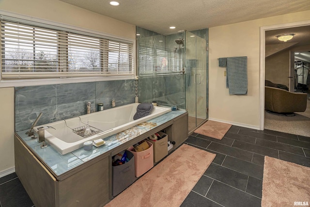 bathroom with a shower stall, a washtub, and a textured ceiling