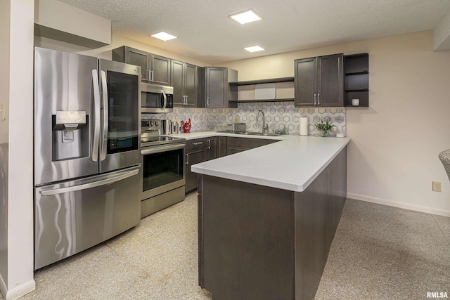 kitchen featuring open shelves, a sink, light speckled floor, stainless steel appliances, and a peninsula