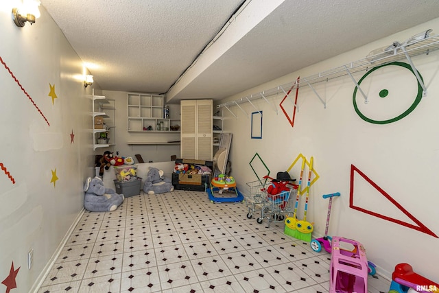 playroom with baseboards and a textured ceiling