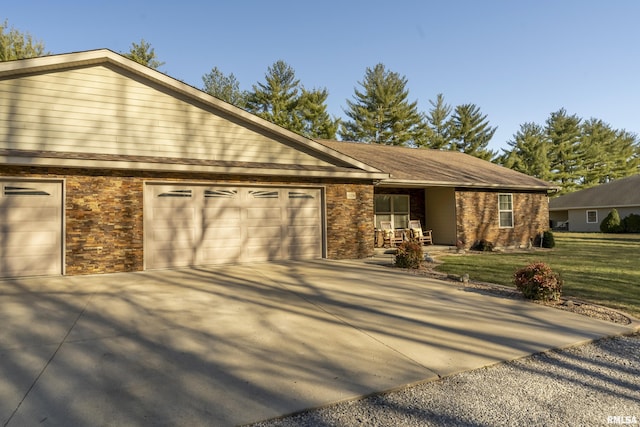 ranch-style home with stone siding, an attached garage, concrete driveway, and a front yard