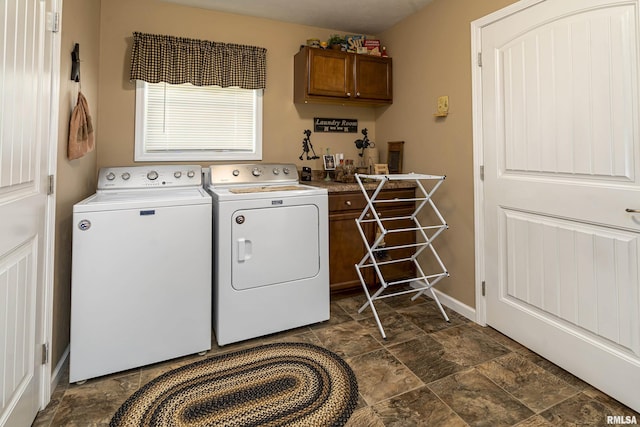 washroom with cabinet space, independent washer and dryer, stone finish flooring, and baseboards