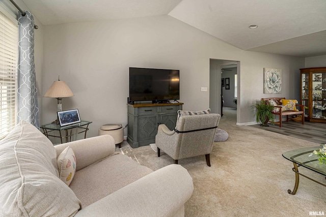 living room featuring vaulted ceiling, light colored carpet, and baseboards