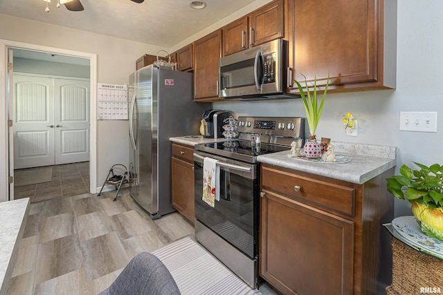 kitchen with light countertops, brown cabinetry, a ceiling fan, and appliances with stainless steel finishes