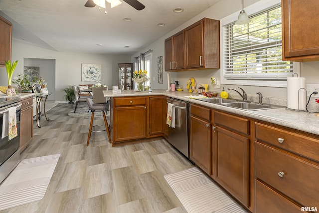 kitchen with light countertops, brown cabinets, a peninsula, stainless steel appliances, and a sink