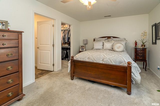 bedroom with visible vents, a walk in closet, a closet, carpet flooring, and ceiling fan