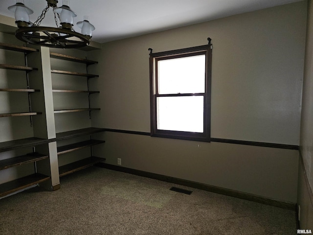 empty room featuring carpet, baseboards, visible vents, and a chandelier