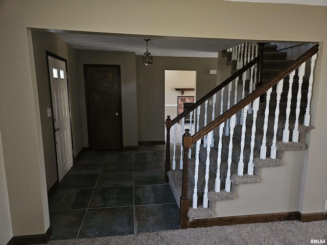 tiled entryway featuring stairs and baseboards