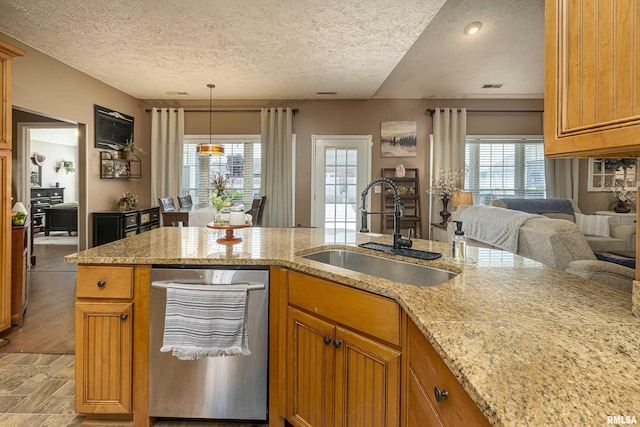 kitchen featuring visible vents, a sink, brown cabinetry, light stone countertops, and dishwasher