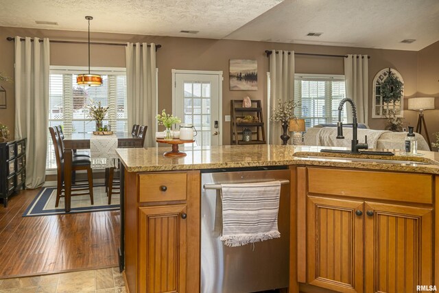 kitchen with a sink, visible vents, brown cabinets, and stainless steel dishwasher