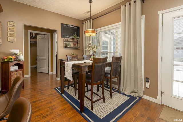 dining space featuring wood finished floors, baseboards, and a textured ceiling