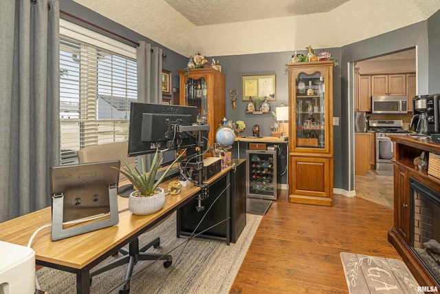 office area with baseboards, wine cooler, a textured ceiling, and wood finished floors