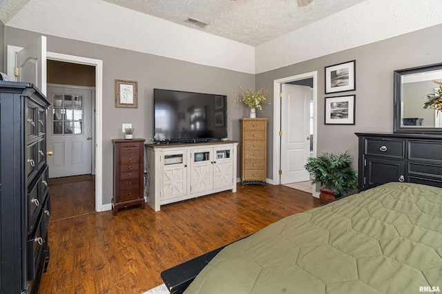 bedroom with dark wood-type flooring, baseboards, visible vents, and lofted ceiling