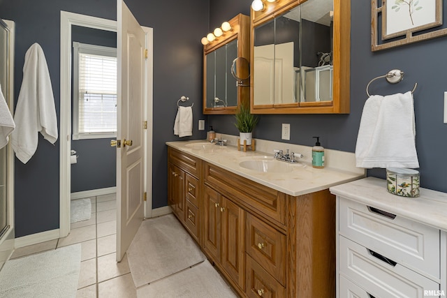 full bathroom featuring a sink, baseboards, double vanity, and tile patterned floors