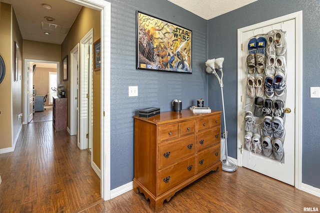 corridor featuring baseboards and wood finished floors