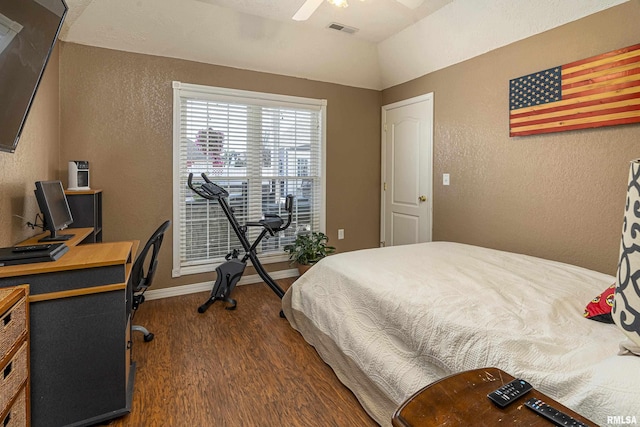 bedroom with dark wood finished floors, visible vents, baseboards, and a textured wall