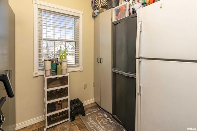 kitchen featuring baseboards and freestanding refrigerator