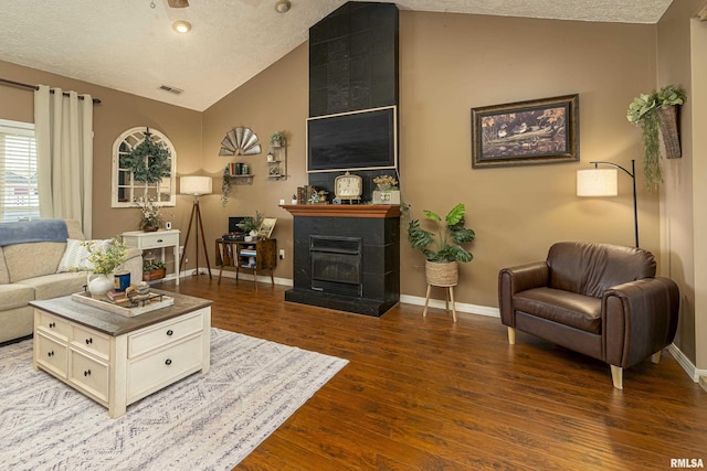 living room with visible vents, wood finished floors, a large fireplace, baseboards, and vaulted ceiling