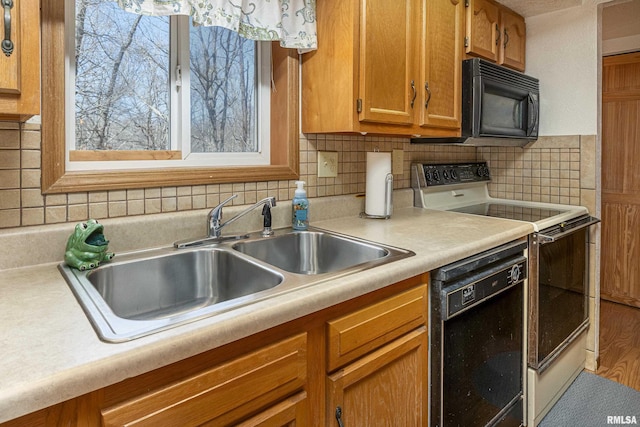 kitchen with black appliances, light countertops, backsplash, and a sink