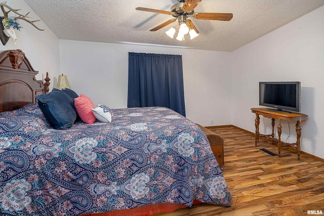 bedroom featuring baseboards, a textured ceiling, a ceiling fan, and wood finished floors